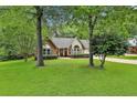 Traditional brick home featuring a lush green lawn and mature trees providing shade at 108 Shawville Ln, Peachtree City, GA 30269