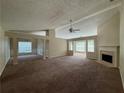 Open-concept living area with fireplace, large windows, plush carpet, and classic chandelier in the adjacent dining space at 124 Sparkling Spring Trl, Mcdonough, GA 30252