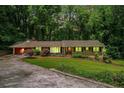 Charming home boasts a lush, green lawn and a circular driveway surrounded by mature trees at 5170 Oxbow Rd, Stone Mountain, GA 30087