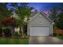 Charming two-story home features a well-maintained lawn, attached two-car garage, and mature landscaping at twilight at 2173 Beacon Crest Dr, Buford, GA 30519