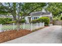 Exterior view of the home with a concrete driveway, landscaped yard, and a white picket fence at 220 Sisson Ne Ave, Atlanta, GA 30317