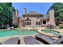 Resort-style backyard featuring a pool, hot tub, and outdoor lounge area with lush greenery at 8525 Saint Marlo Fairway Drive, Duluth, GA 30097