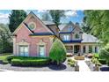 Elegant brick home with well-manicured landscaping, a circular driveway, and charming fountain feature at 8525 Saint Marlo Fairway Drive, Duluth, GA 30097