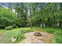 Secluded backyard featuring a cozy fire pit surrounded by mature trees and landscaping at 890 Oriole Se Ln, Marietta, GA 30067