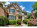 Beautiful two-story brick home featuring a charming balcony, lush landscaping, and classic architectural details at 935 Brookline Way, Alpharetta, GA 30022