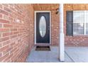 Close-up of front door with oval glass insert, decorative light fixture and red brick surround at 538 Shadowmoore Dr, Riverdale, GA 30274