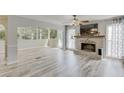 Open living room featuring a brick fireplace, large windows, and light gray flooring at 2920 Waverly Place Dr, Dacula, GA 30019