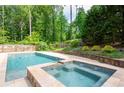 Backyard pool with attached spa and stone border is surrounded by trees for backyard privacy at 355 Clark Creek Pass, Acworth, GA 30102