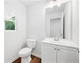 Compact half bathroom featuring a white vanity, toilet, and a window for natural light at 132 2Nd Nw St, Atlanta, GA 30318