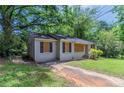 Charming exterior view of a compact home with a brick foundation, boarded-up windows, and mature trees at 1906 Oak Valley Rd, Decatur, GA 30035