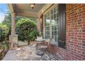 Cozy covered porch with stone flooring, brick columns, and a quaint seating area at 5925 Water Mark Dr, Cumming, GA 30040