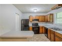 Functional kitchen with wooden cabinets and black appliances offering practical cooking space at 6185 Marbut Farms, Lithonia, GA 30058