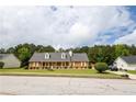 Charming brick home featuring a welcoming front porch, yellow shutters, and lush green lawn at 40 Oak Hill Dr, Covington, GA 30016
