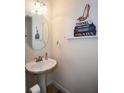 Cozy powder room with a pedestal sink, round mirror, and chic fashion-themed decor at 6245 Hickory Lane Cir, Union City, GA 30291