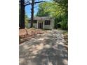 View of home's driveway framed by mature trees and lush foliage leading up to a quaint residence at 6399 Boca Grande Blvd, Forest Park, GA 30297