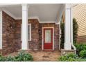 Charming front porch with stone pillars and a welcoming red front door entrance at 4230 Glen Vista Ct, Duluth, GA 30097