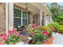 Inviting front porch with seating area, surrounded by vibrant roses and manicured landscaping at 871 Wisteria View Ct, Dacula, GA 30019