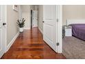 Hallway with hardwood floors leading to a bedroom, showcasing an open doorway and a glimpse of bedroom at 871 Wisteria View Ct, Dacula, GA 30019
