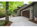 Side exterior view showcasing the attached garage, front porch, and wooded surroundings of the home at 1560 Bubbling Creek Ne Rd, Atlanta, GA 30319