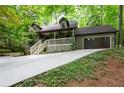 Exterior view of home with front porch, lush trees, two-car garage and nicely manicured landscaping at 1560 Bubbling Creek Ne Rd, Atlanta, GA 30319