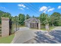 Long driveway leading to a home with a gated entrance, a three-car garage, and lush green surroundings at 1461 Leach Dr, Lawrenceville, GA 30045