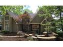 Inviting home exterior with stone accents, mature trees, professionally landscaped front yard, and well-lit entrance at 3800 Schooner Rdg, Alpharetta, GA 30005