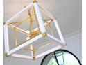 Close up of a stylish, geometric chandelier with white and gold accents, enhancing the room's decor at 3379 Rennes Ne Dr, Brookhaven, GA 30319