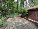 Concrete patio area adjacent to a brick home with a glimpse of the wooded backyard at 2226 Medfield Ne Trl, Atlanta, GA 30345