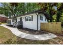 Landscaped front yard featuring a bright white home with contrasting dark trim, walkway and fence at 4720 Shoshonee Trl, College Park, GA 30349