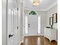 Bright entryway showcasing a hardwood floor, white front door, and a stylish cabinet at 208 Magnolia Leaf Dr, Woodstock, GA 30188
