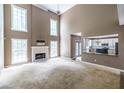 Bright living room with high ceilings, a fireplace, and an open view into the adjacent kitchen at 1130 Timbercreek Ct, Alpharetta, GA 30005