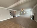 Open living room with a fireplace, fan, and neutral carpet adjacent to a staircase at 3488 Woodshade Dr, Loganville, GA 30052