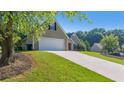 Spacious driveway leading to an attached garage, surrounded by green landscaping and mature trees at 1625 Alcovy River Dr, Dacula, GA 30019