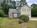 Well-maintained two-story home with green shutters, and a brick accent wall, surrounded by lush greenery at 5517 Rock Shoals Way, Atlanta, GA 30349