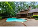 Inviting backyard pool area with brick retaining wall, lush landscaping, and serene wooded surroundings at 9995 Huntcliff Trce, Atlanta, GA 30350