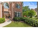 Close-up of the front of a brick home featuring an arched window, covered porch, and well-maintained landscaping at 963 Hawk Creek Trl, Lawrenceville, GA 30043