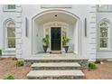 Inviting front entrance featuring stone steps, black door with transom window, and potted plants at 605 Buttercup Trce, Johns Creek, GA 30022