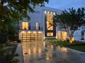 Modern home with a black framed garage door, second story balcony and lit landscape at dusk at 2385 Nesbitt Dr, Brookhaven, GA 30319