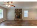 Living room with wood flooring, ceiling fan, and stone fireplace, offering a cozy and inviting atmosphere at 6015 Sumit Nw Ct, Kennesaw, GA 30152