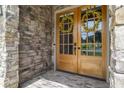 Close-up of a wooden front door with glass panes, flanked by stone walls at 407 Estates View Dr, Acworth, GA 30101