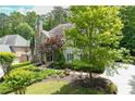 Home featuring a stone chimney, beautiful landscaping, lush trees and greenery, and circular driveway at 4101 Rickenbacker Ne Dr, Atlanta, GA 30342