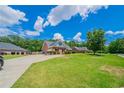 Charming brick home with lush green lawn and long driveway under a partly cloudy sky at 1480 Holly Brook Rd, Snellville, GA 30078