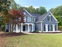 Inviting two-story home with gray siding, lush landscaping, and a cozy front porch entrance at 219 Maple Creek, Woodstock, GA 30188