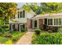 Inviting two-story home with a brick facade, complemented by lush greenery and well-maintained landscaping at 6825 Castleton Dr, Atlanta, GA 30328