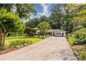 Charming home with a long driveway, beautiful lawn, and mature trees providing ample shade at 6825 Castleton Dr, Atlanta, GA 30328
