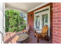 Covered porch featuring brick flooring, two wooden chairs, and a side table, perfect for outdoor relaxation at 3049 Brightwood Se Ln, Marietta, GA 30067