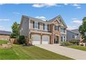 Side view of a well-maintained two-story home featuring a manicured lawn and a paved driveway at 5415 Fieldfreen Dr, Cumming, GA 30028