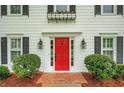 Close-up of a bright red front door with sidelights, flanked by manicured bushes and charming decor at 1384 Independence Way, Marietta, GA 30062