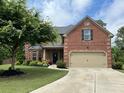 Red brick home with an attached two-car garage and well-maintained lawn at 2430 Tack Hill Ct, Dacula, GA 30019