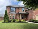 Charming two-story brick home featuring a manicured lawn and lush landscaping at 2430 Tack Hill Ct, Dacula, GA 30019
